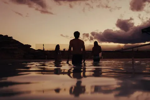 People stand in a pool during sunset.