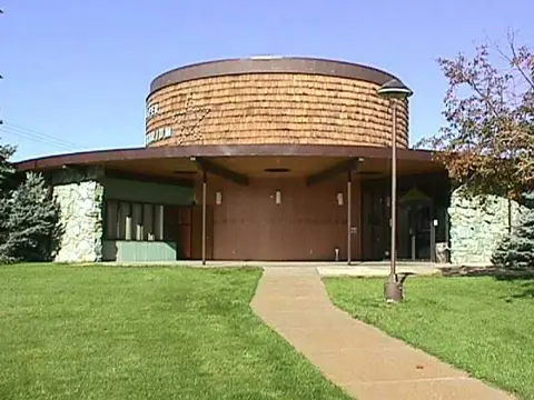 An exterior view of a modern round building with a walkway leading up to it.