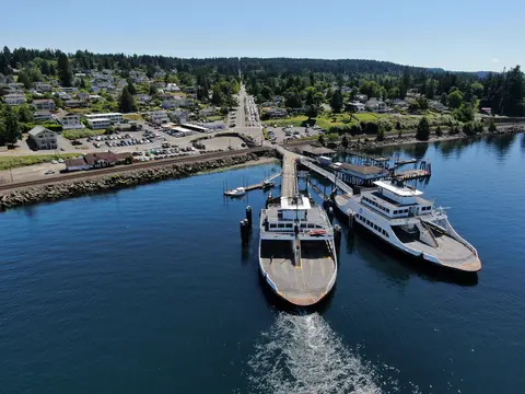 Aerial view of two ferries docked at a pier near a coastal town.