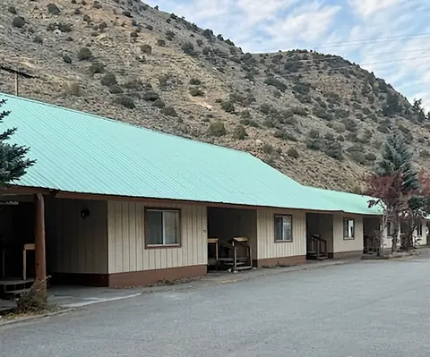 A single-story motel building sits at the base of a dry, rocky mountain.