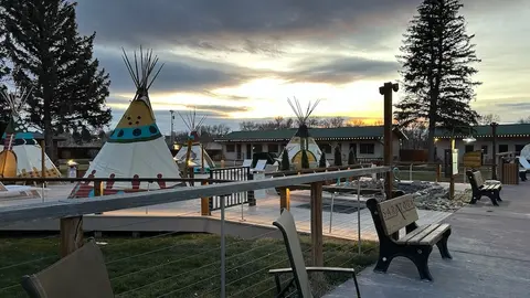 An outdoor resort area with tipis and benches at sunset.