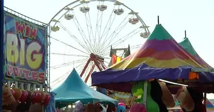A carnival featuring a ferris wheel and colorful tents.
