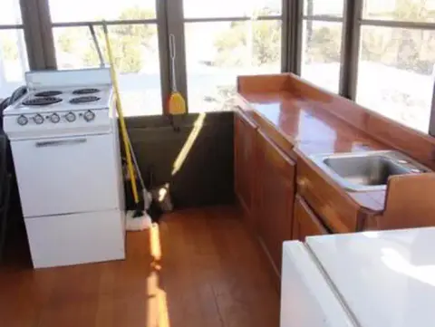 An indoor view of a kitchen area with a white stove, wooden cabinets, and a sink.
