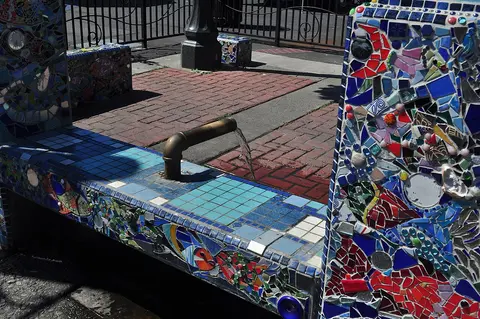 A public water fountain decorated with colorful mosaic tiles.
