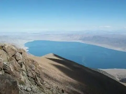 A high-angle view of a large blue lake surrounded by mountainous terrain.