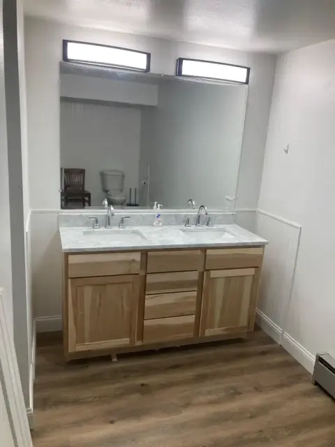 A bathroom with a wooden double vanity and a large mirror.