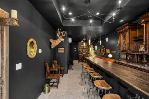 A view of the interior of a bar with dark walls and a long wooden bar counter.