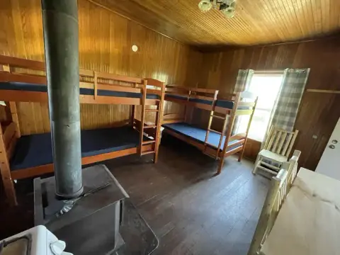 An interior view of a room with wooden bunk beds and a wood stove.