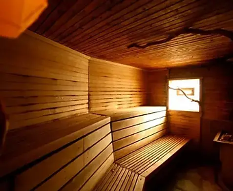 A wooden sauna interior with tiered benches and warm lighting.