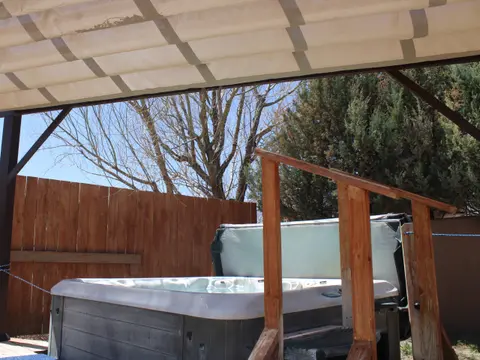 A hot tub with a wooden staircase under a canopy outside.