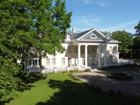 A large historic house with columns and a front porch viewed from outside.