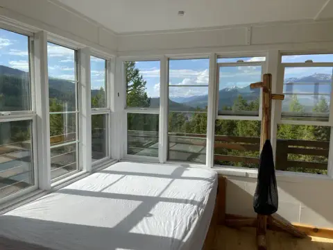 An interior room with large windows showing a mountain landscape view.