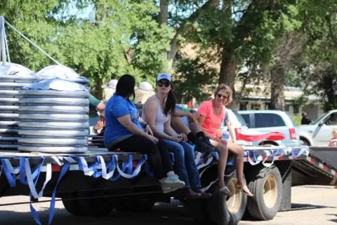 A group of people sitting on the back of a flatbed trailer decorated with ribbons.