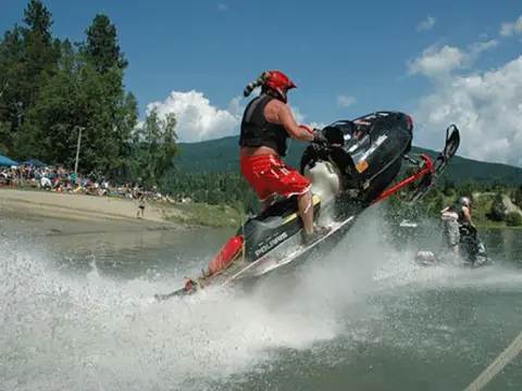 A person rides a watercraft that looks like a snowmobile across a lake.