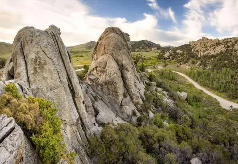 A wide-angle photograph of granite rock formations and a landscape with a dirt road.