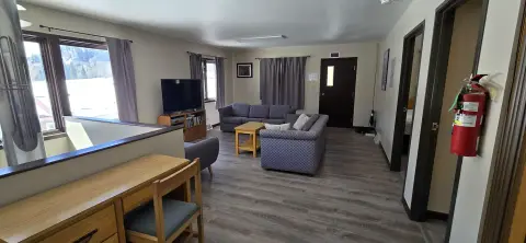 A furnished interior living room with couches, a television, and a wooden desk.