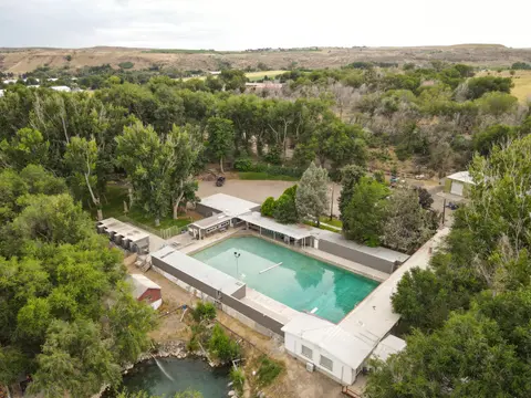 An aerial view of an outdoor swimming pool surrounded by trees and hills.