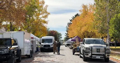 People walking down a street lined with trucks and vendor tents during an outdoor event.