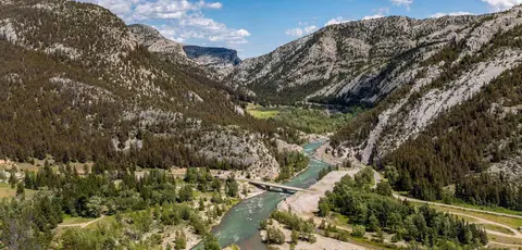 A river flows through a wide canyon with forested mountain slopes.
