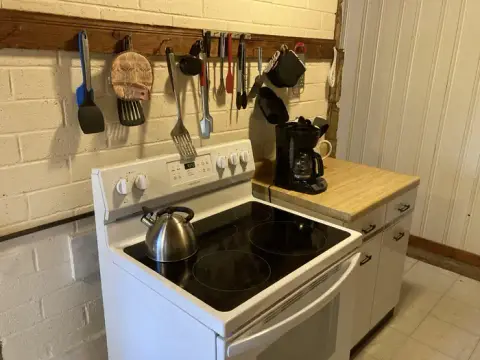 A kitchen interior showing a stove, counter, and hanging utensils.
