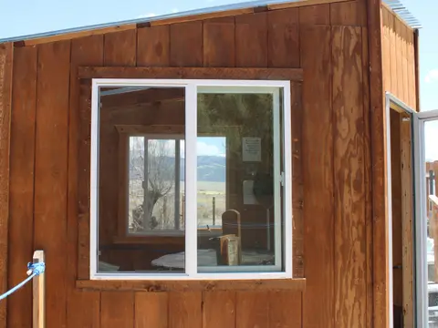 Exterior view of a wooden shed with a large white-framed window.