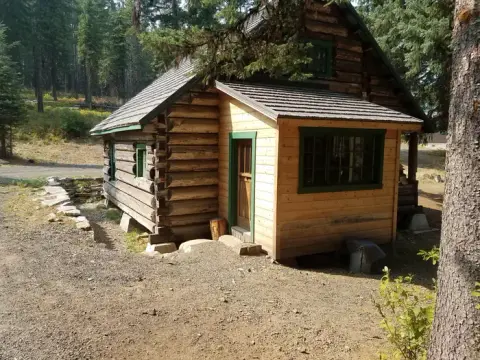 A log cabin sits in a clearing surrounded by trees.