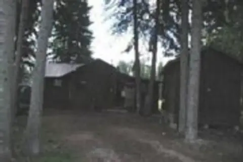 A dark, blurry photo of rustic cabins nestled among trees.