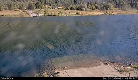 A view of a lake and a boat ramp with a ferry in the distance.