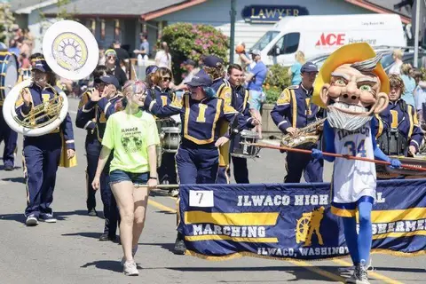 A marching band and mascot participate in a street parade.