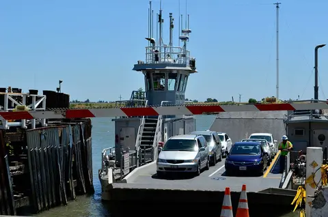 A ferry is docked with several cars loaded on its deck.