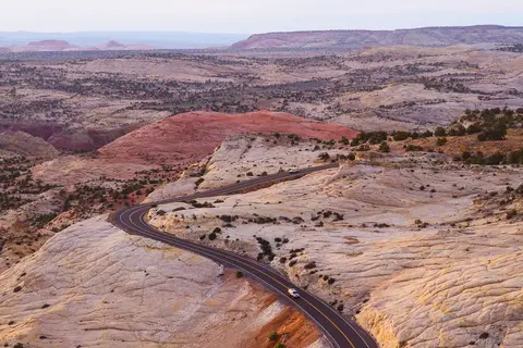 A winding road cuts through an expansive desert landscape with rocky terrain and hills.