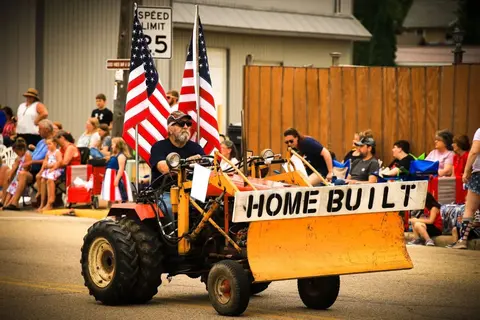 A man drives a homemade tractor in a parade.