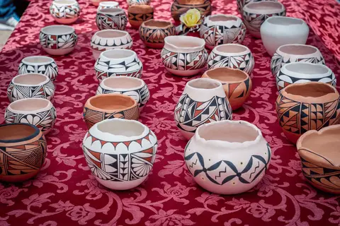 A collection of handmade patterned pottery bowls arranged on a patterned red cloth.