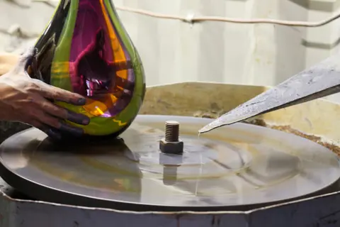 A person working with glass on a lapidary wheel.