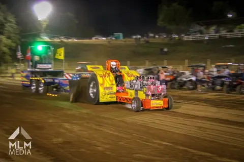 A modified tractor pulls a weighted sled at a tractor pull event.