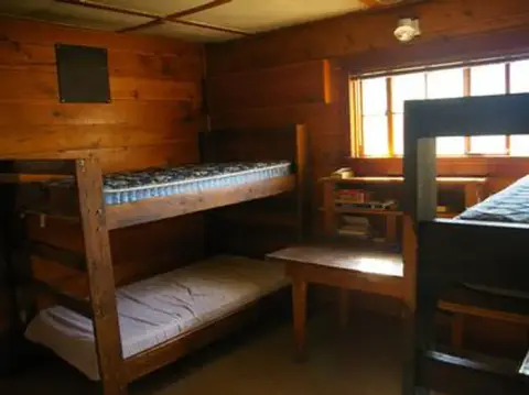 An interior view of a room with wooden bunk beds and a window.