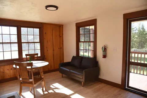 An interior view of a room with a small dining table, chairs, and a couch.