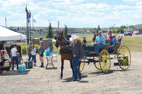A person leads a horse pulling a carriage with passengers outside.