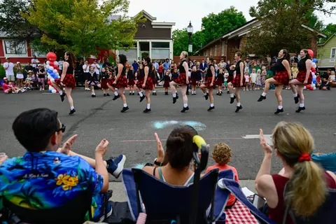 A troupe of dancers performs in the street for a crowd of onlookers.