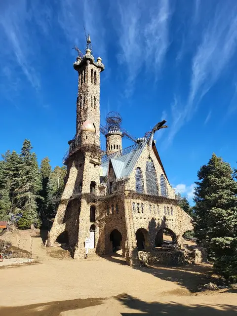 A stone castle-like structure stands outdoors under a blue sky.