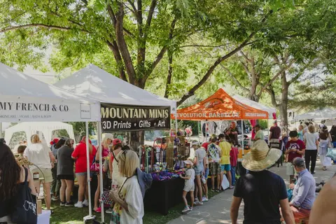 A photo showing a crowded outdoor market with tents and shoppers.