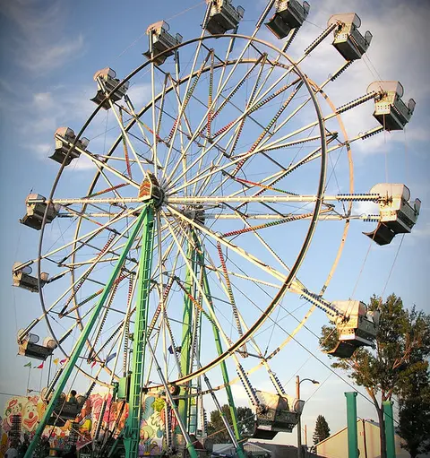 A Ferris wheel stands against a blue sky with scattered clouds.