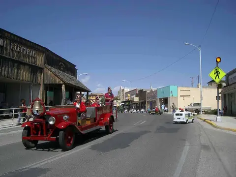 A vintage red fire truck drives down a town street during a parade.