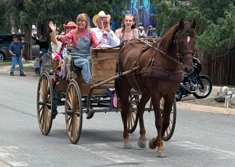 People riding in a horse-drawn wagon on a street.