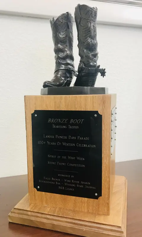 A bronze boot trophy mounted on a wooden base with a plaque.