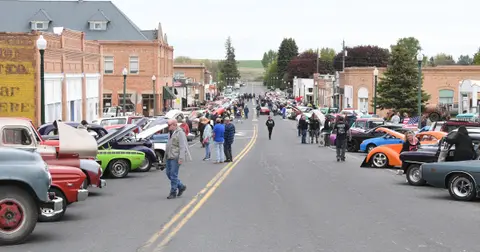 A street lined with classic cars and people gathered for an event.
