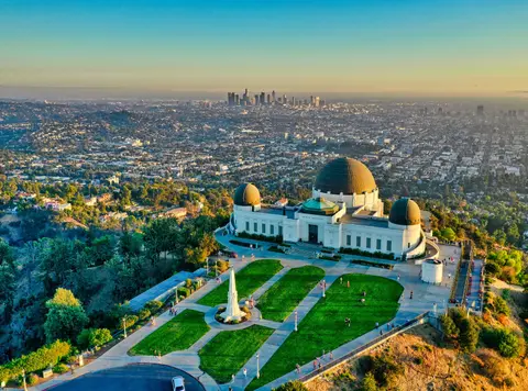 An aerial view of an observatory with a city skyline in the distance.