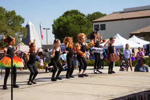 Children performing dance routines on an outdoor stage.