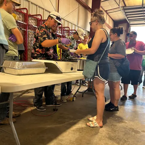 People waiting in line to be served food at a buffet table.