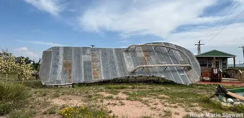 A large sculpture of a flip-flop sandal stands outside in a field.